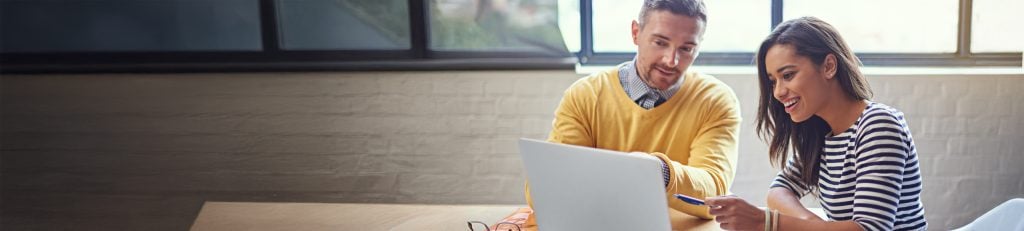 Two people talking whilst looking at laptop