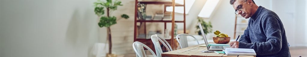 Man sitting at laptop writing notes