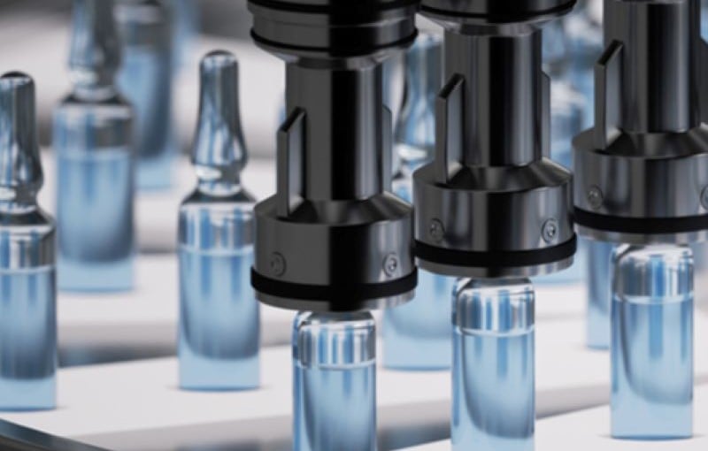 Automated machinery handling rows of glass vials on a production line